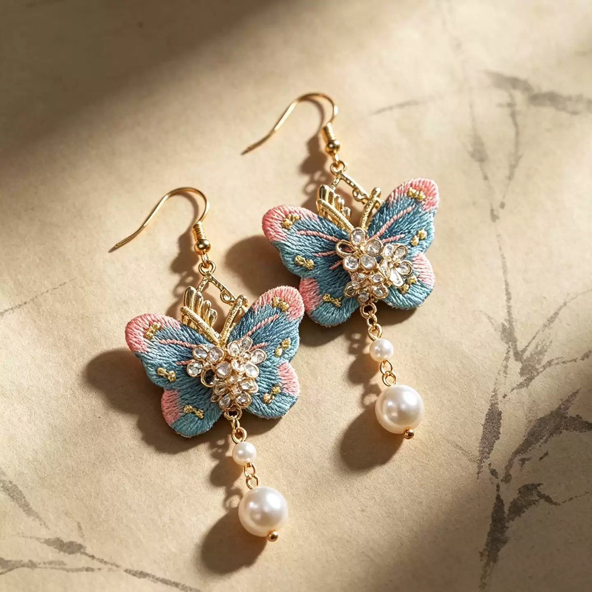 Pair of embroidered butterfly earrings on a light background