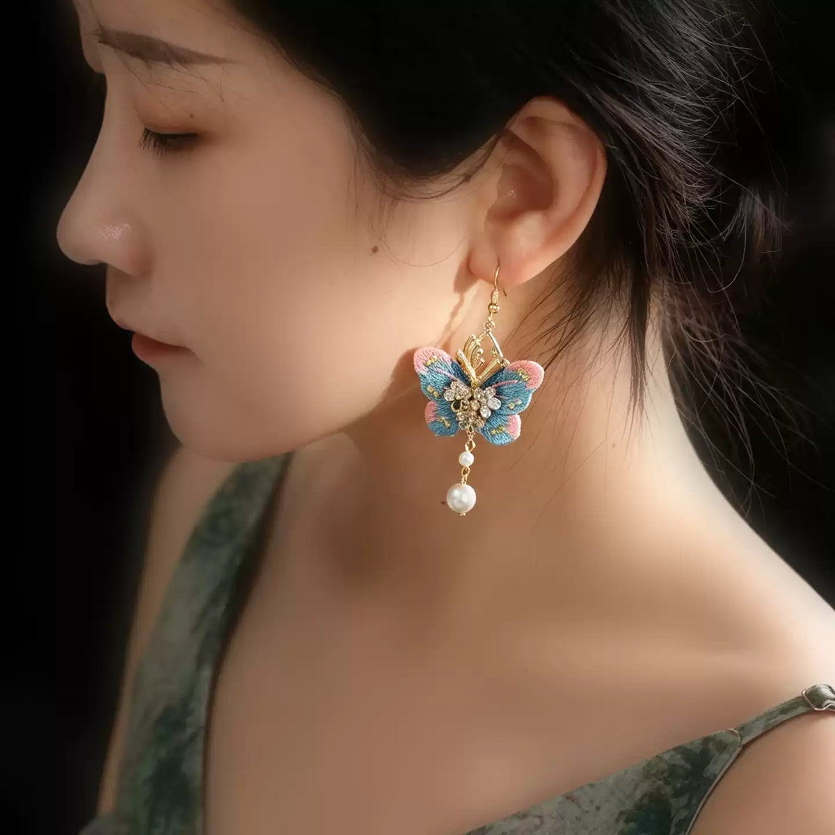 Model wearing a pink and blue embroidered butterfly tassel earring