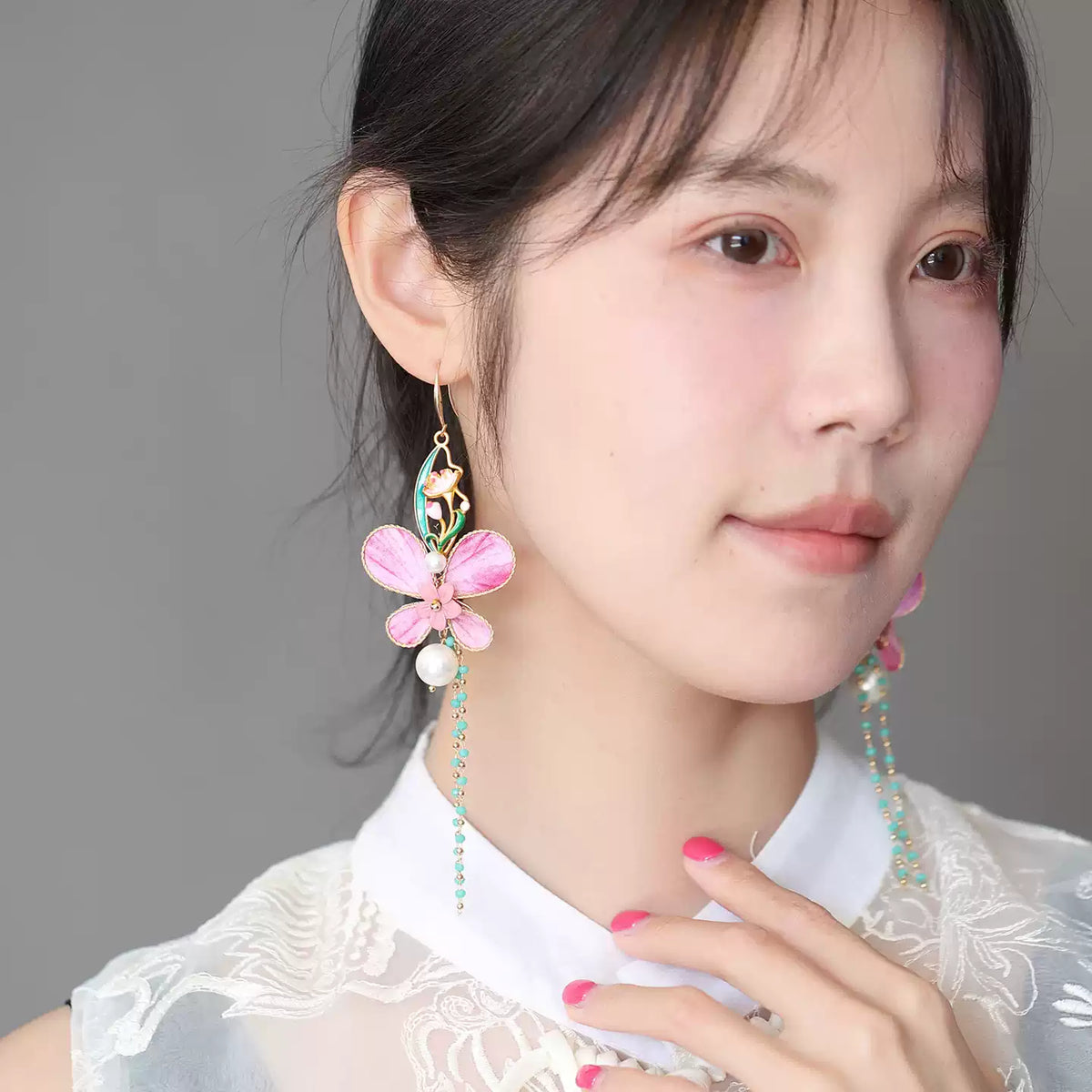 Pair of pink butterfly earrings displayed on a branch