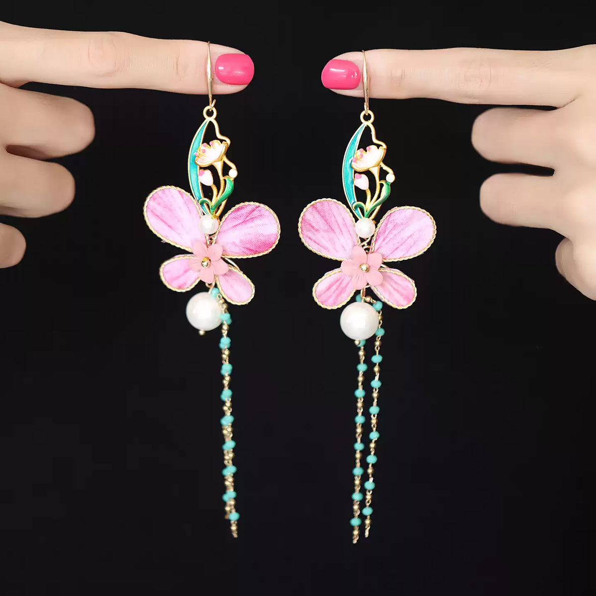 Pair of pink butterfly earrings held for scale and detail