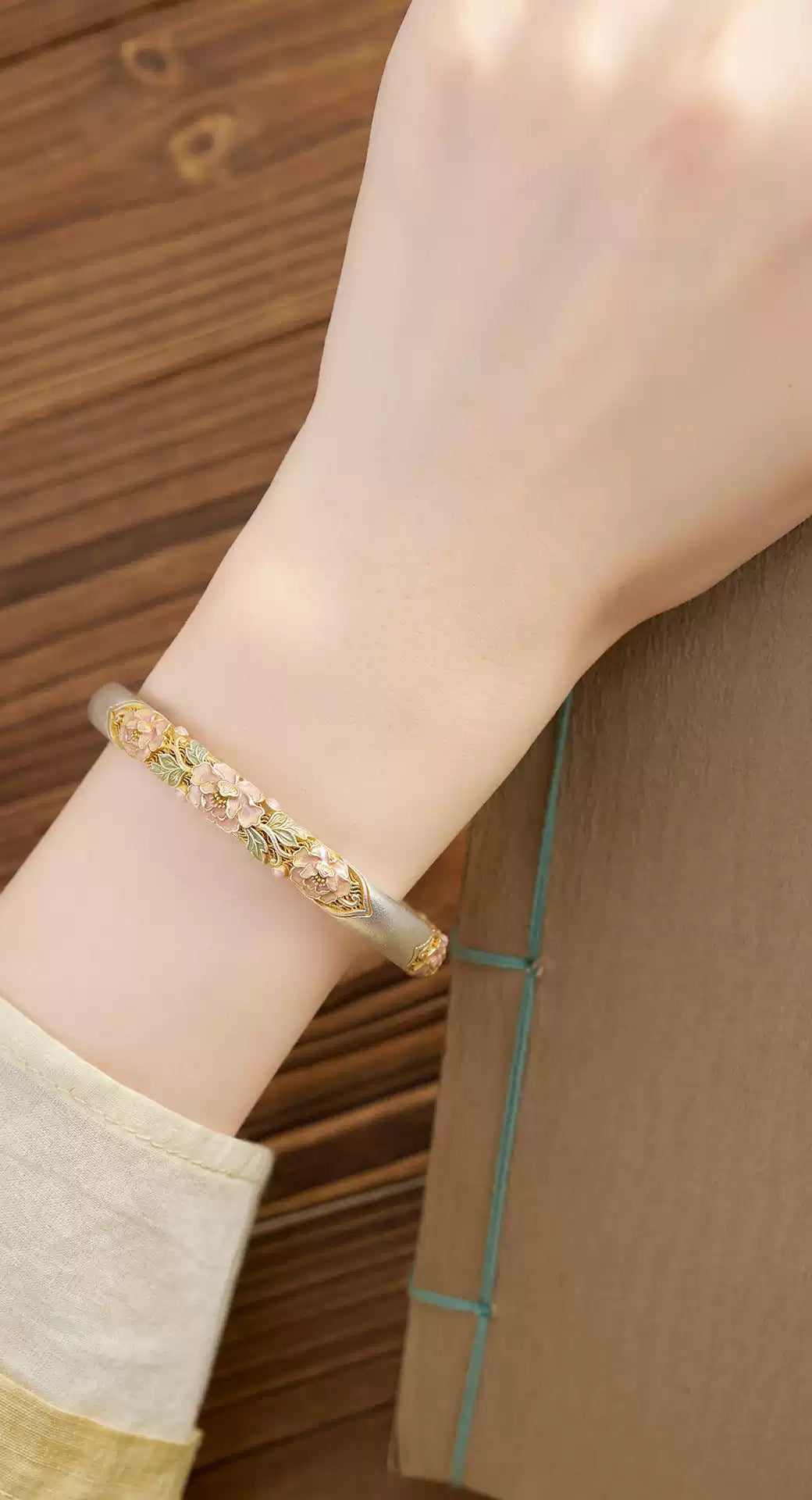 Pink peony enamel cuff bracelet worn on wrist, angled view