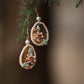 Close view of pink shell flower, green leaf and faux pearl earring details
