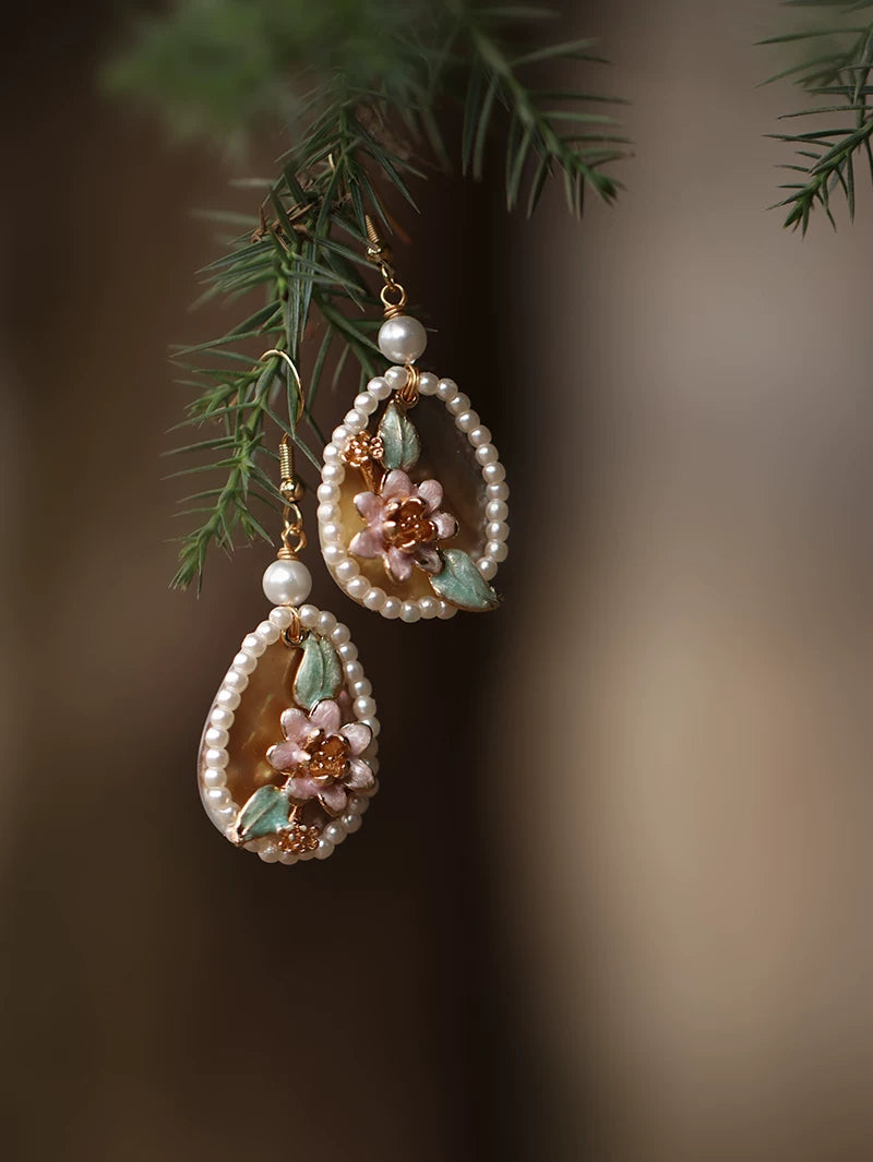 Close view of pink shell flower, green leaf and faux pearl earring details