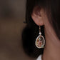 Side view of a pink shell flower drop earring worn on the ear