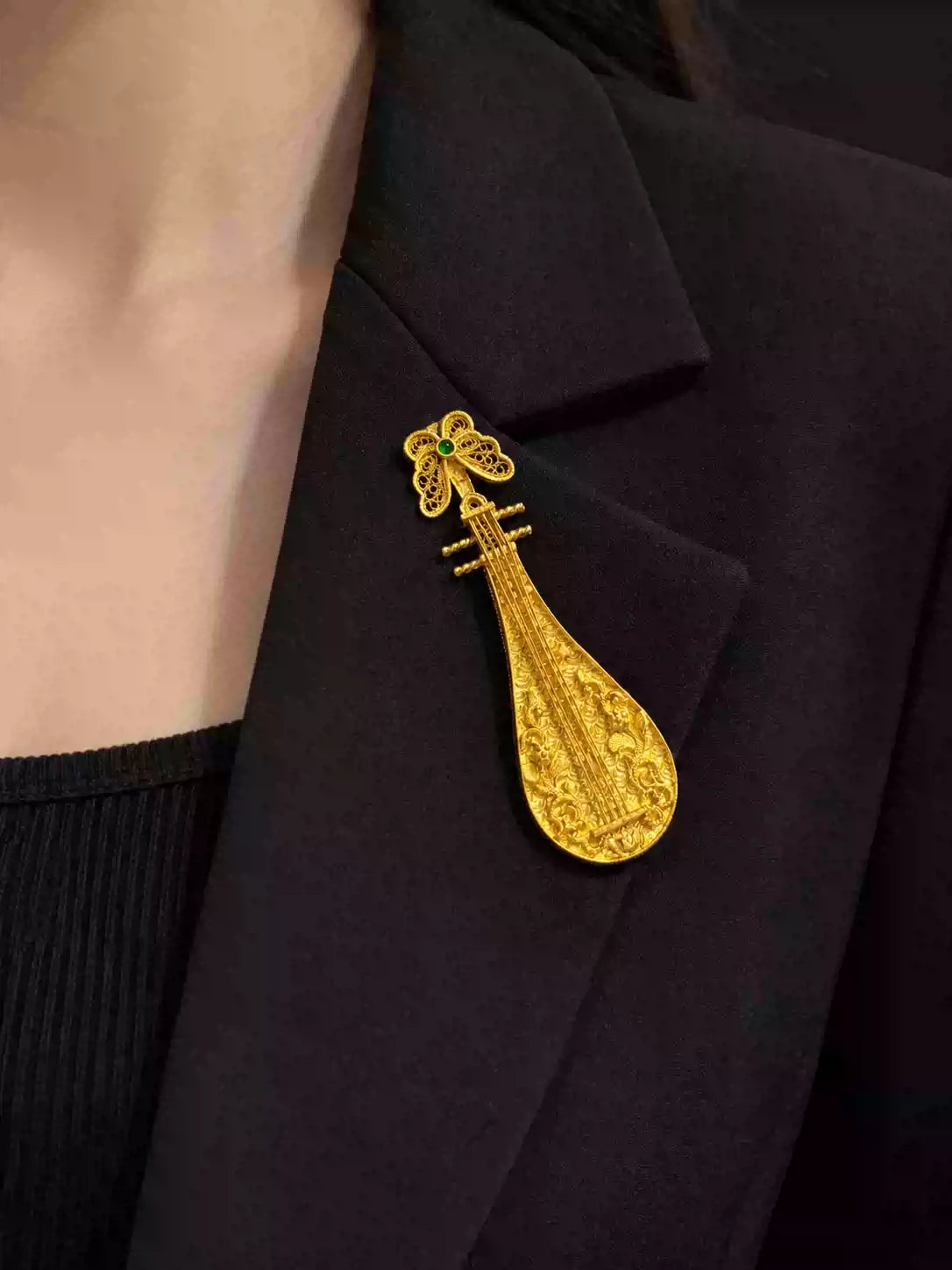 Pipa-shaped copper brooch worn on a dark jacket lapel