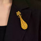 Close view of the gold-tone pipa brooch on a jacket