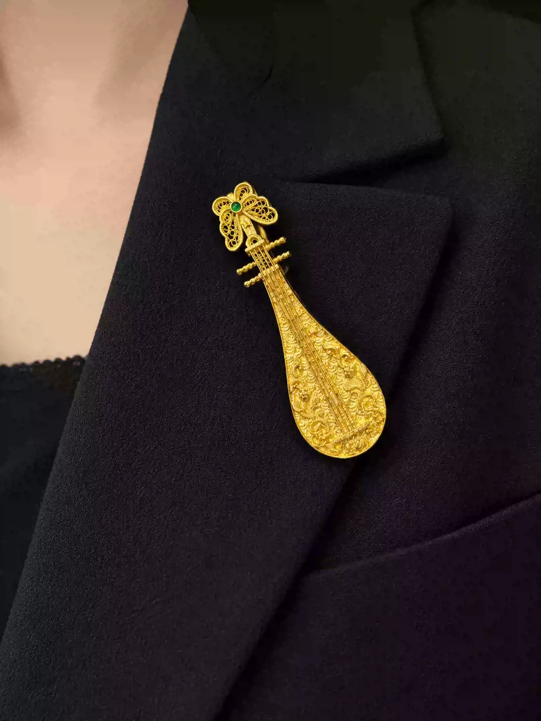 Pipa-shaped copper brooch pinned to a jacket