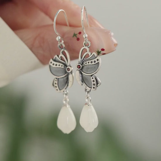 Product video showing butterfly drop earrings with white teardrop pendants