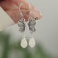 Product video showing butterfly drop earrings with white teardrop pendants