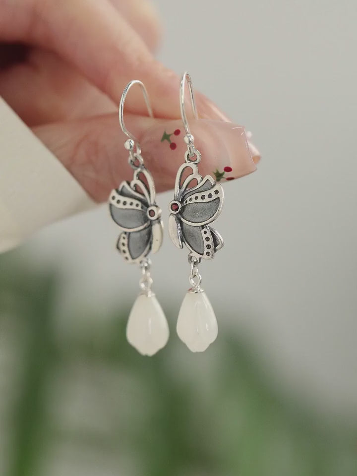 Product video showing butterfly drop earrings with white teardrop pendants