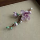 Angled view of the floral brooch with a large bloom, smaller buds, and leafy branch