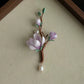 Full view of the pale purple flower branch brooch with green leaves and dangling beads