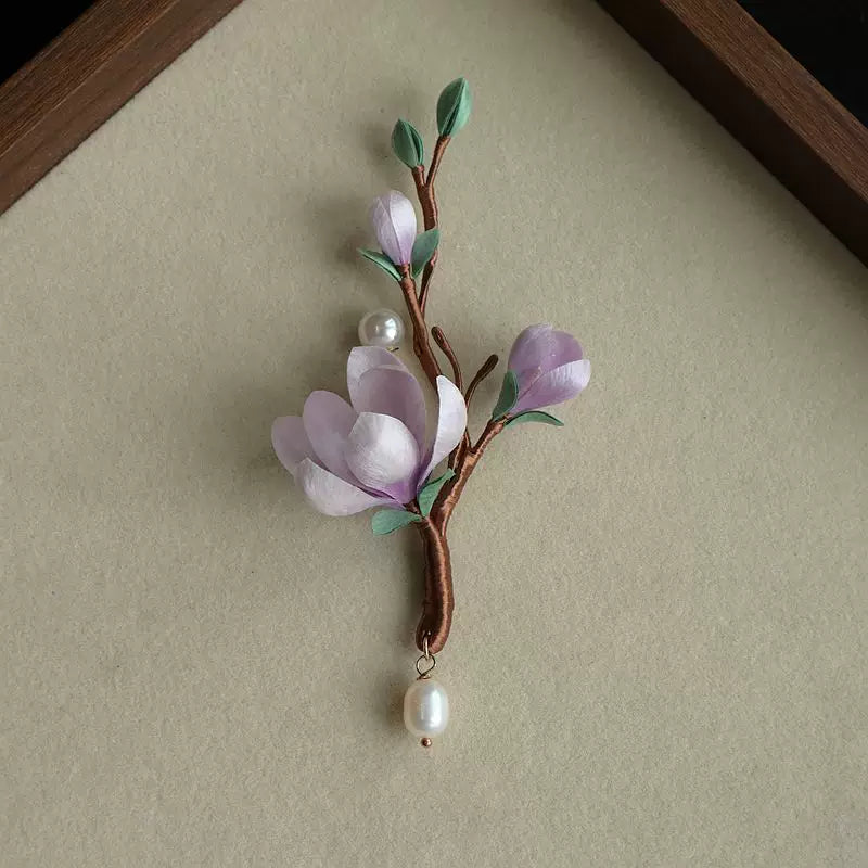 Full view of the pale purple flower branch brooch with green leaves and dangling beads