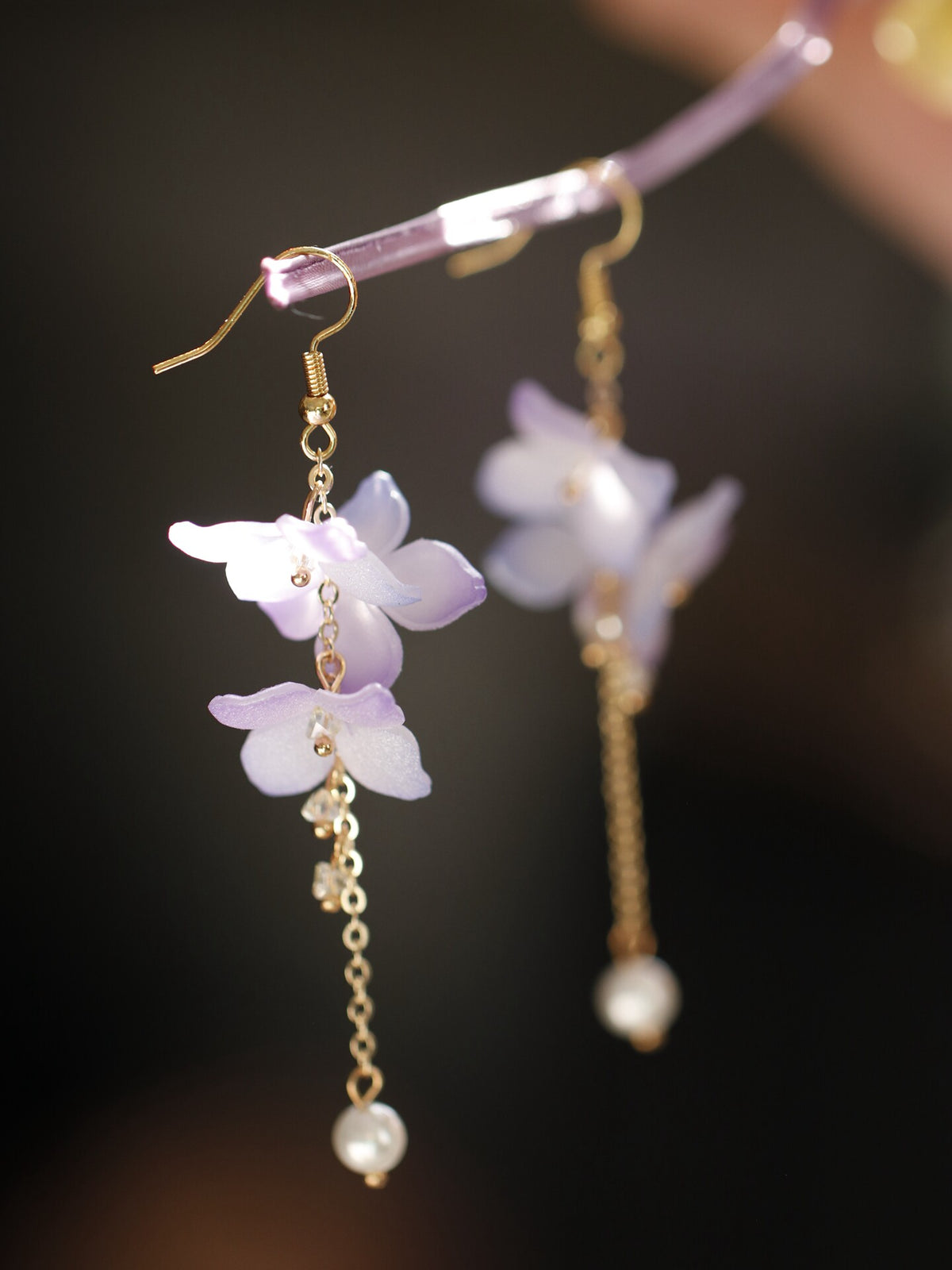 Close-up of a purple hydrangea earring and chain detail