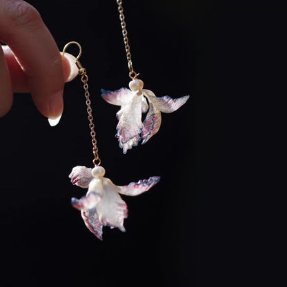 Pair of purple iris-inspired leather flower drop earrings against a dark background