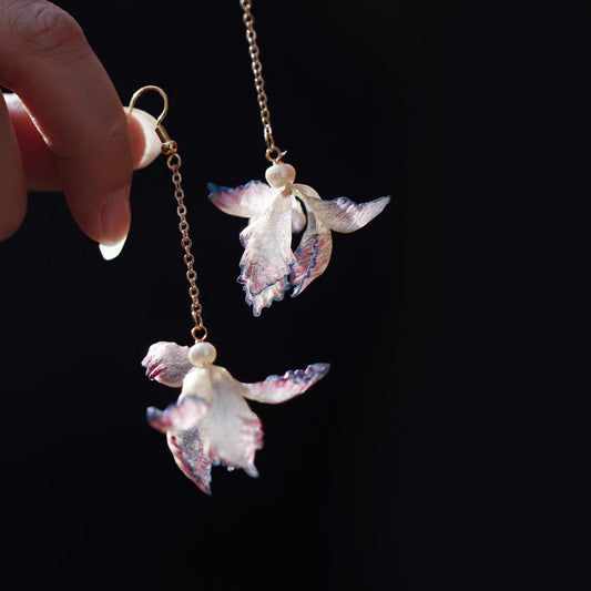 Pair of purple iris-inspired leather flower drop earrings against a dark background