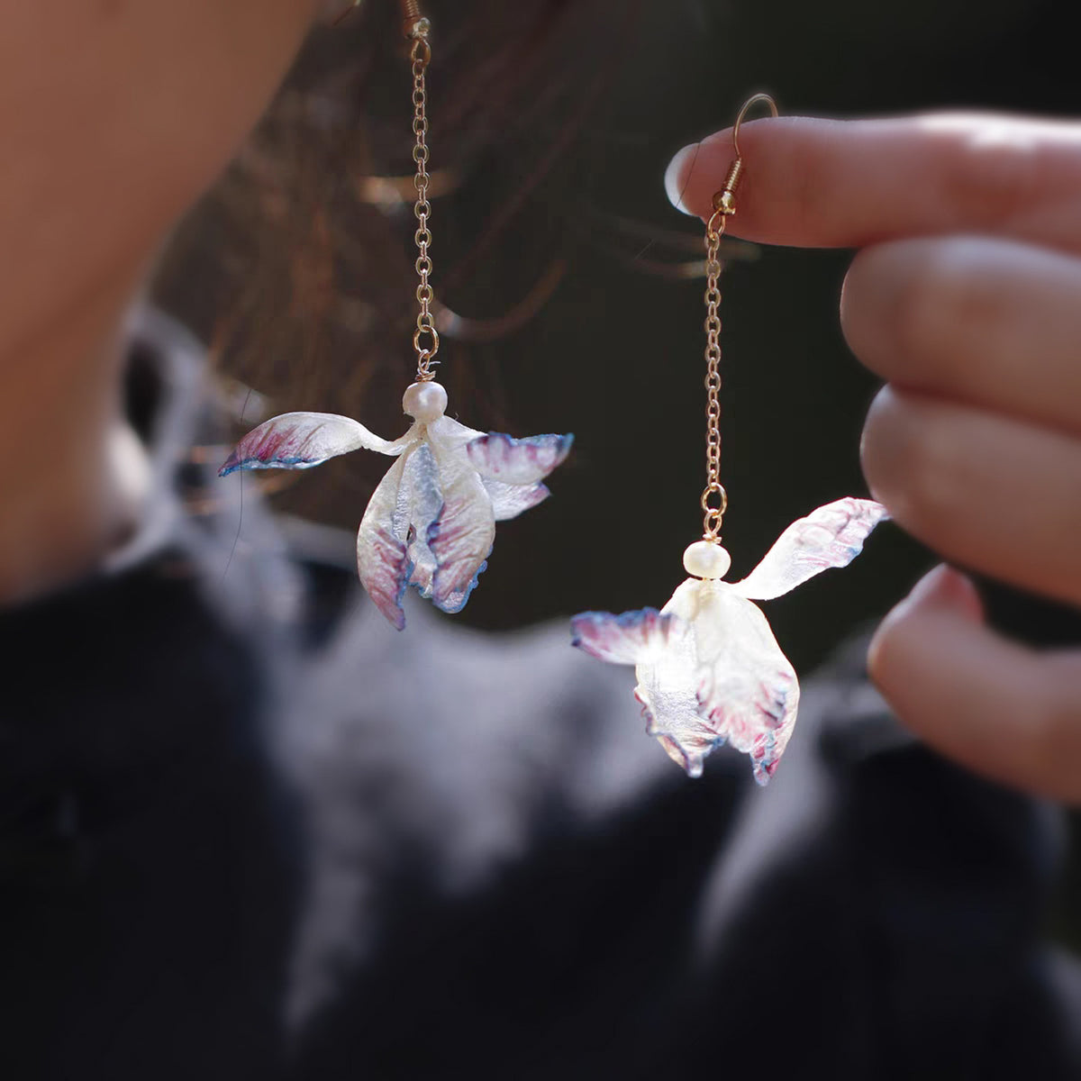 Pair of iris flower drop earrings shown in hand