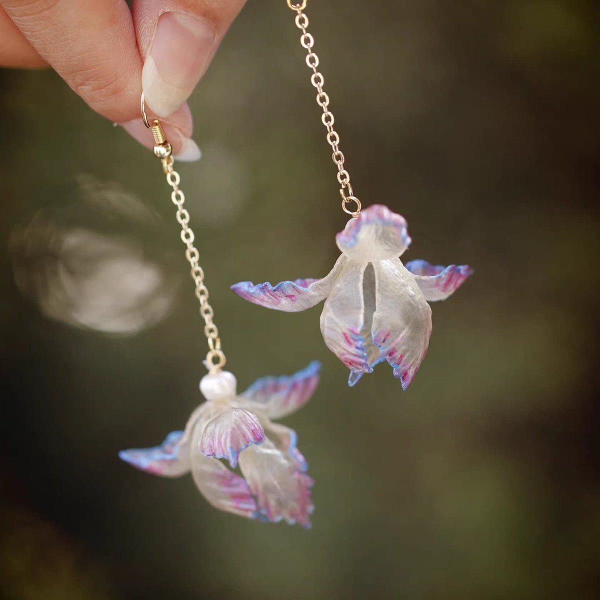Full-length view of purple iris leather flower earrings held in hand