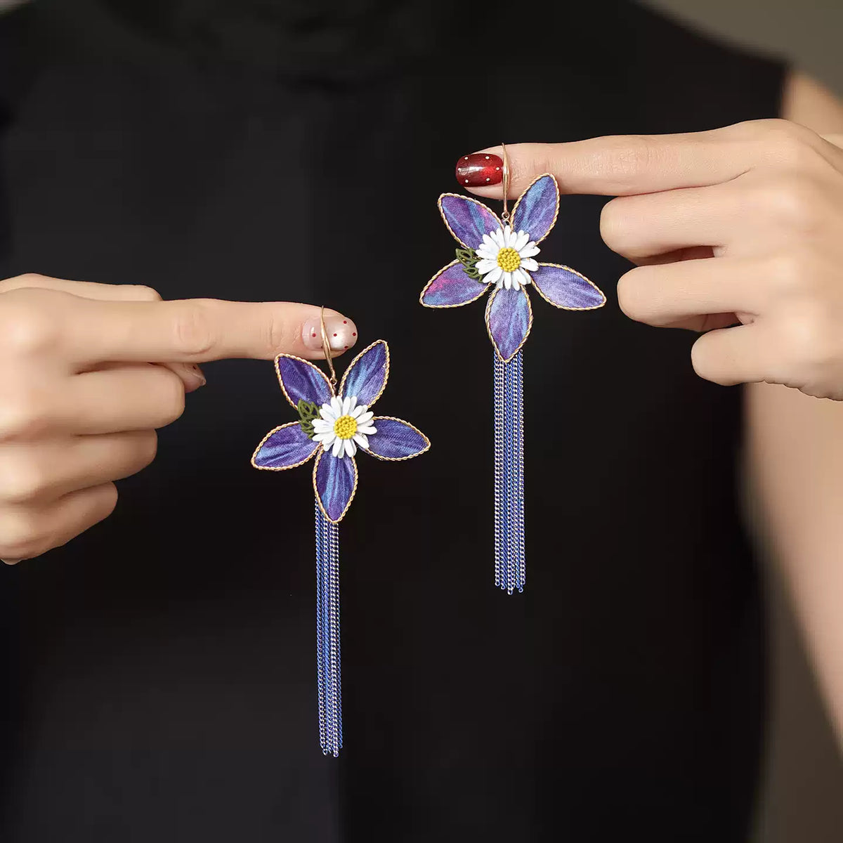 Purple floral drop earrings photographed in hand