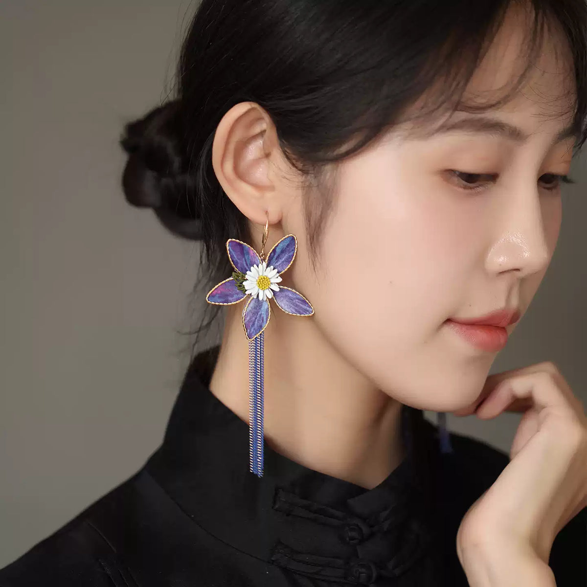 Side view of purple floral drop earring worn