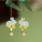 Rabbit floral earrings displayed on a dark green surface