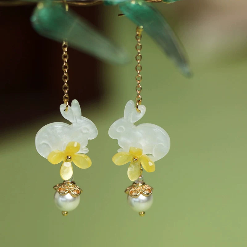 Rabbit floral earrings displayed on a dark green surface