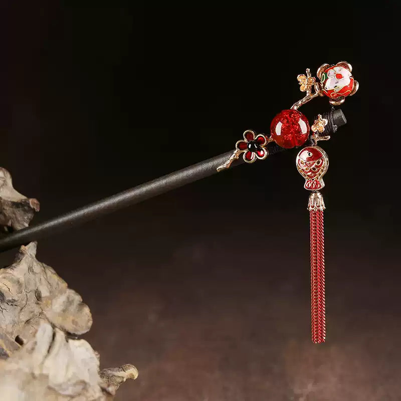 Close-up of wooden hair stick with red fish charm and tassel