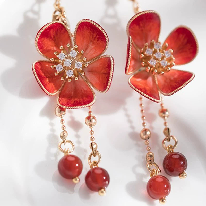 Close-up of the plum blossom drop earrings and red bead tassels