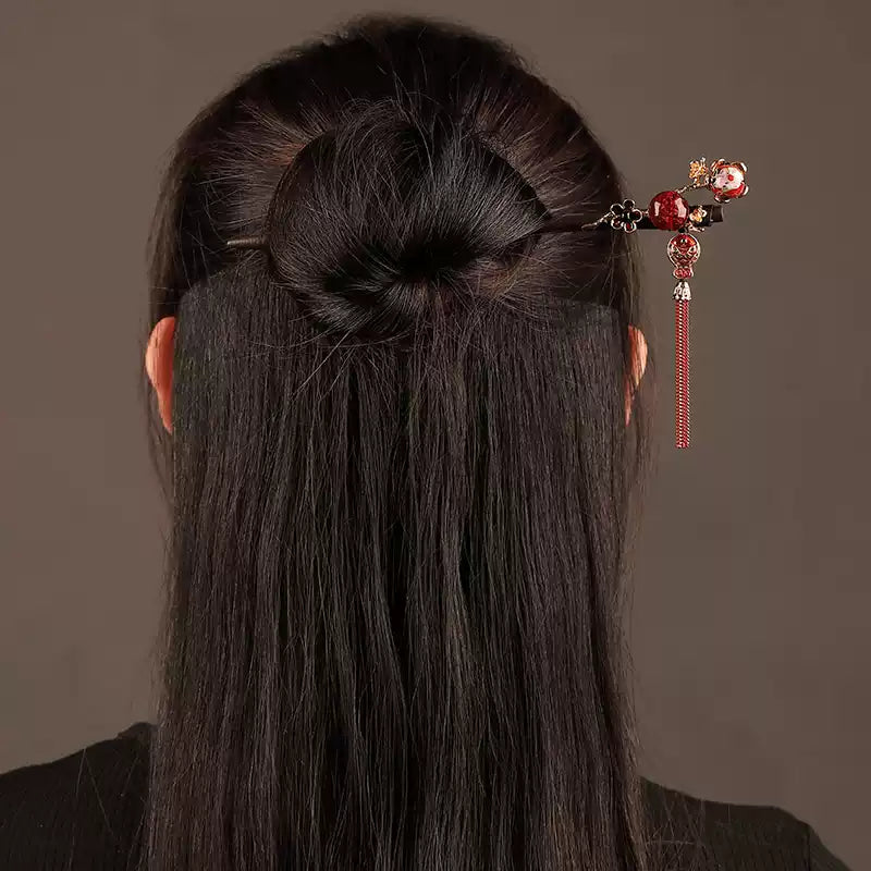 Red tassel hairpin styled in a bun, rear view