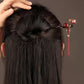 Red tassel hairpin worn in a dark bun, rear view