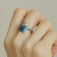 Adjustable koi and begonia ring worn on a finger, with a blue fin detail