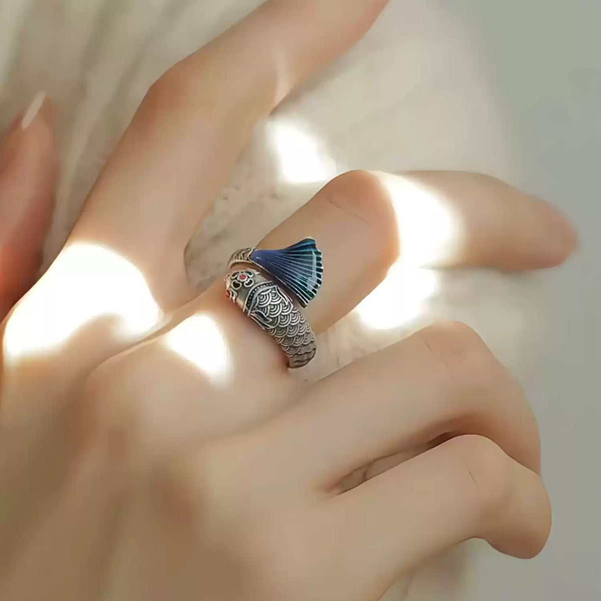 Close view of the open koi ring with a blue fin and silver-tone details