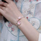Adjustable silver cuff bracelet with pink cherry blossom details worn with embroidered clothing