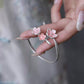 Close-up of pink enamel cherry blossom ornaments on an open silver cuff bracelet