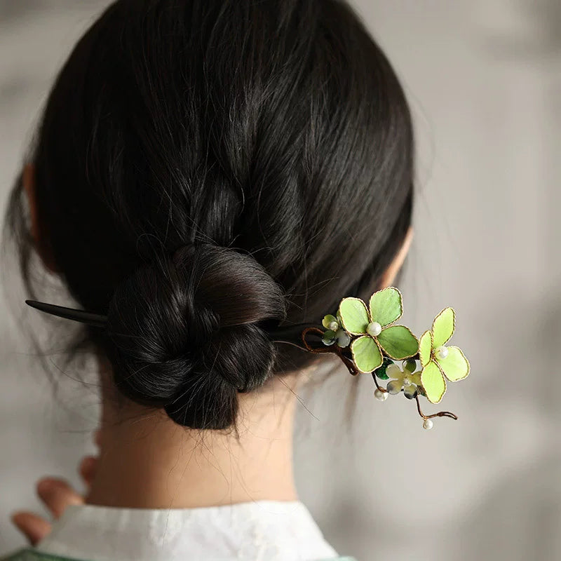 Green blossom wooden hair stick worn in a low bun, back view