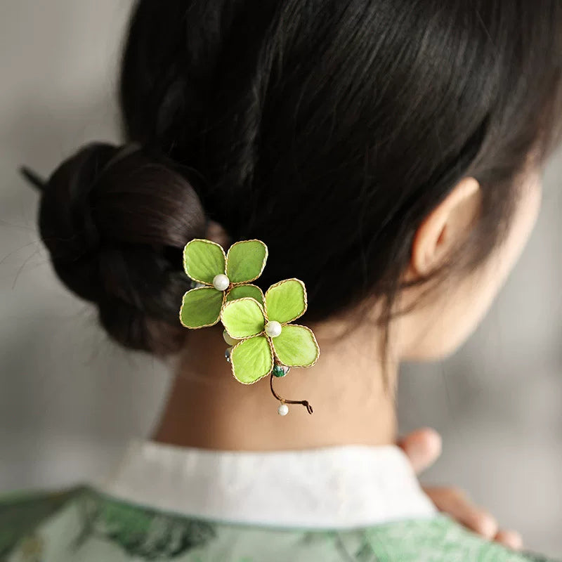 Rear view of a low bun styled with a green floral Chinese-inspired hair stick