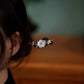 White shell flower on a dark ebony wood hair stick, shown in a bun