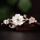 Detailed view of white and pink shell flowers on an ebony-style hair stick