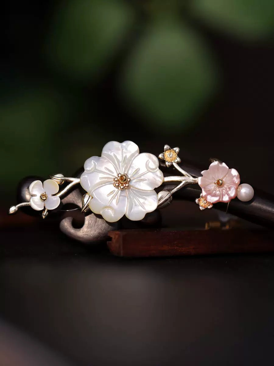 Detailed view of white and pink shell flowers on an ebony-style hair stick
